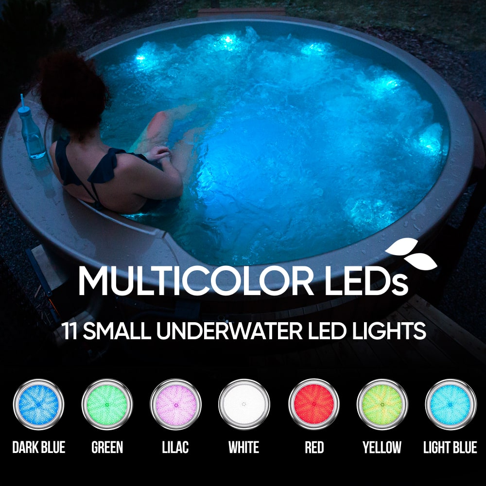 Evening view of round wood fired hot tub with multicolor LED underwater lights and bubbling water