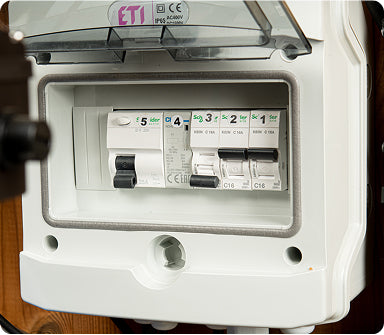 Close-up view of a white electrical breaker panel with four labeled circuit breakers inside a protective enclosure
