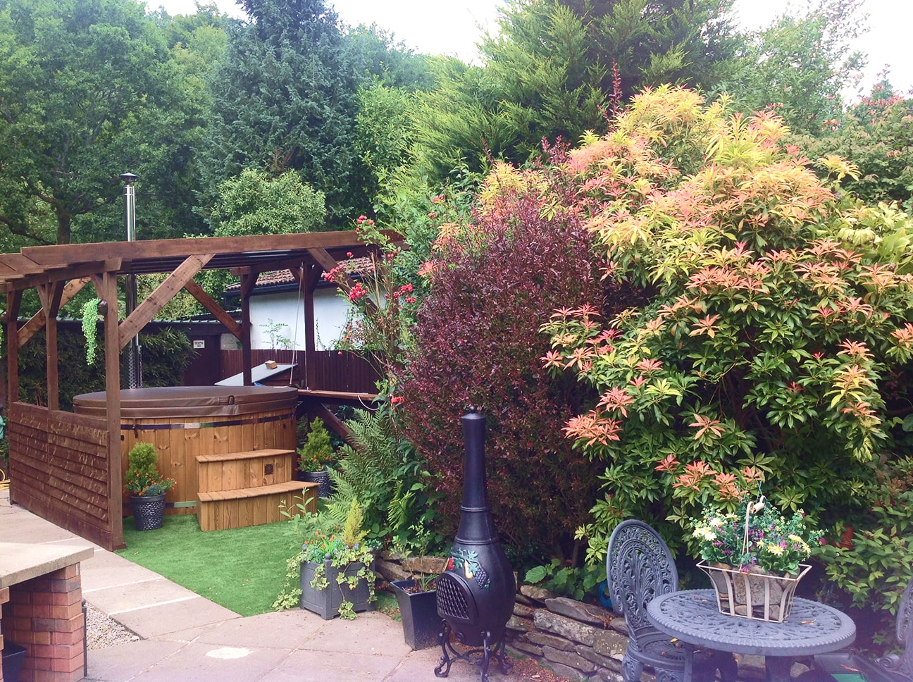 Gardenvity wood fired hot tub in cozy backyard garden surrounded by colorful plants.