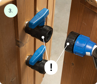 Close-up of two black valves with blue handles mounted on wooden panels next to a blue hose connector attached to another wooden surface