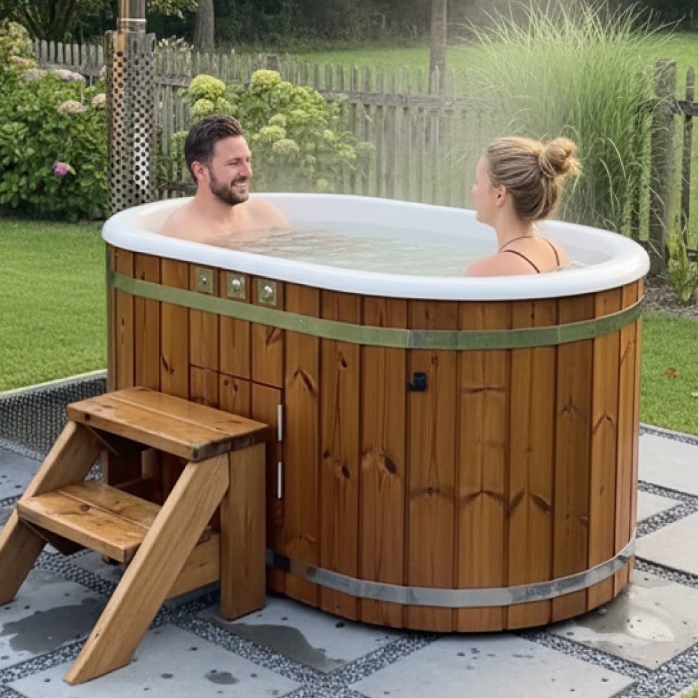 Outdoor side view of wooden hot tub with two people soaking, wooden steps, and garden background with fence and plants